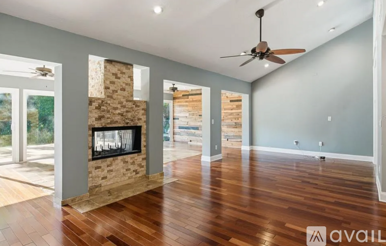 A spacious room with a fireplace and wooden flooring.