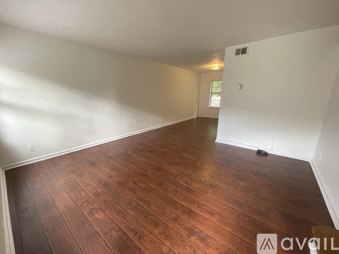 A room with wooden flooring and white walls.