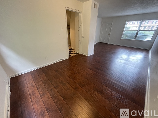 A room with wooden flooring and a doorway leading to another room.