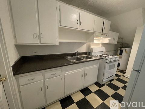 A kitchen with white cabinets and a black and white checkered floor.