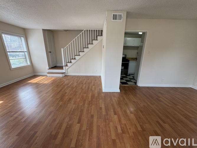 A room with wooden flooring and a staircase leading to another room.