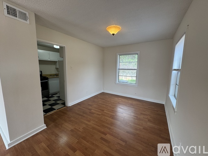 A room with wooden flooring and a window with a view of trees.