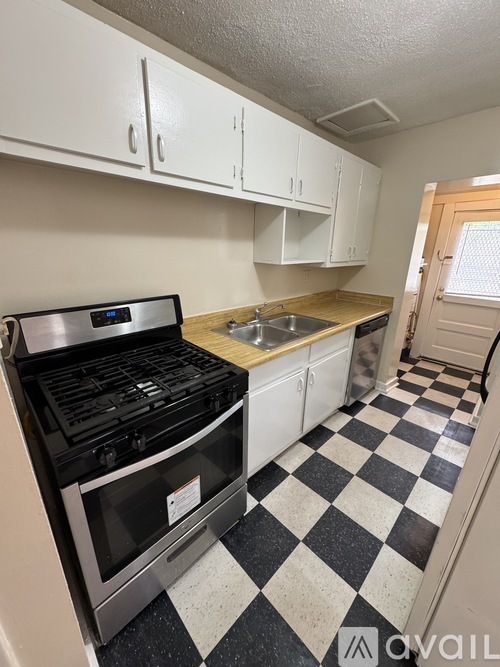 A black and white checkered floor in a kitchen with a stove and sink.