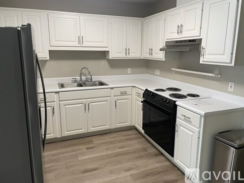A kitchen with white cabinets and a black refrigerator.