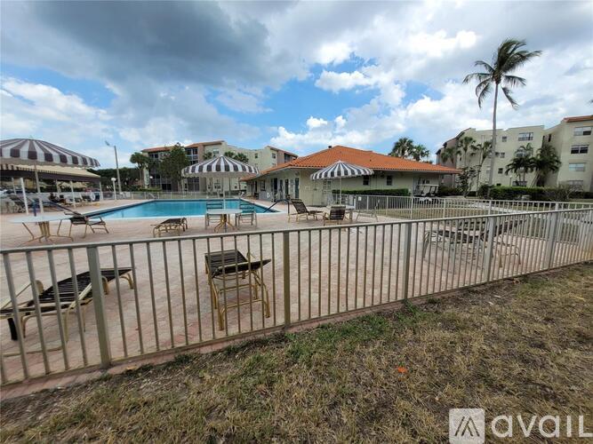 A pool area with chairs and a fence in front of a building.