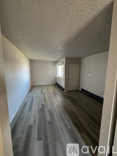 A room with wooden flooring and a door in the background.