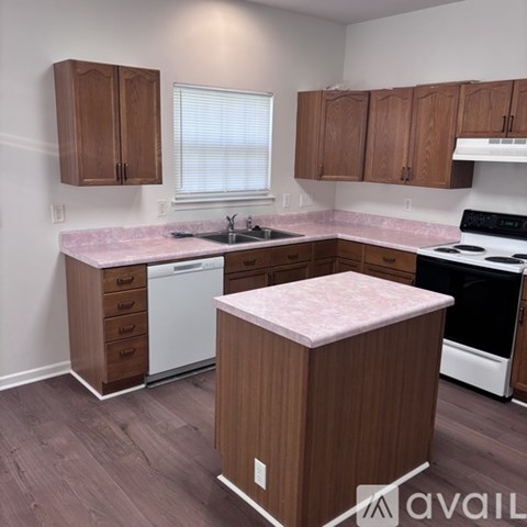 A kitchen with wooden cabinets and a pink countertop.