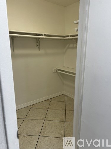 Empty white closet with shelves and tiled floor.
