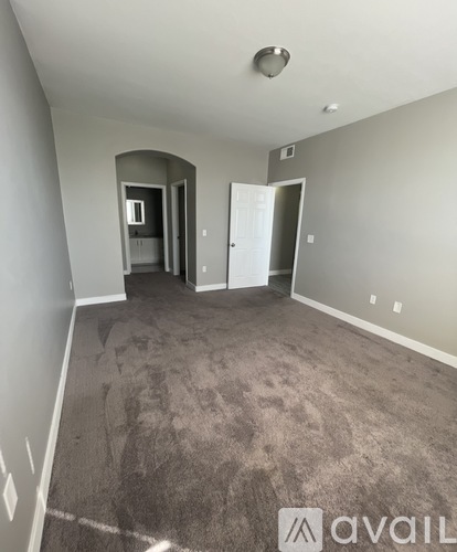 A spacious room with carpeted floor and a doorway leading to another room.