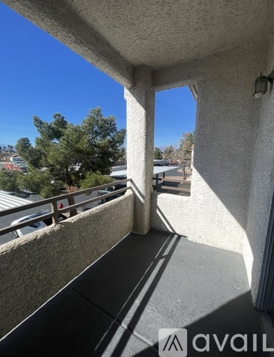 A balcony with a view of a parking lot and trees.