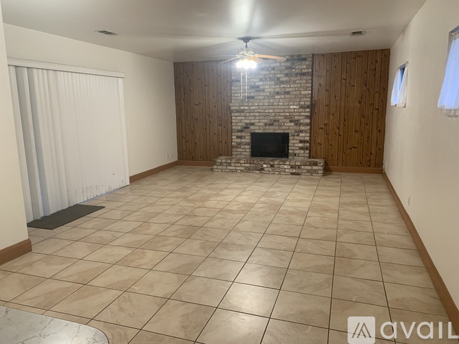 A spacious room with a stone fireplace and tiled flooring.