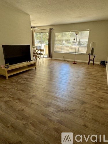A living room with a television and a wooden floor.