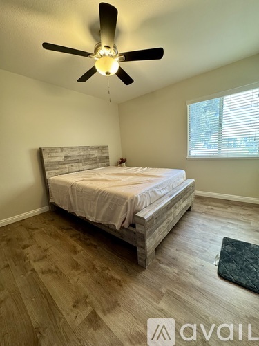 A bedroom with a bed, wooden headboard, and a ceiling fan.