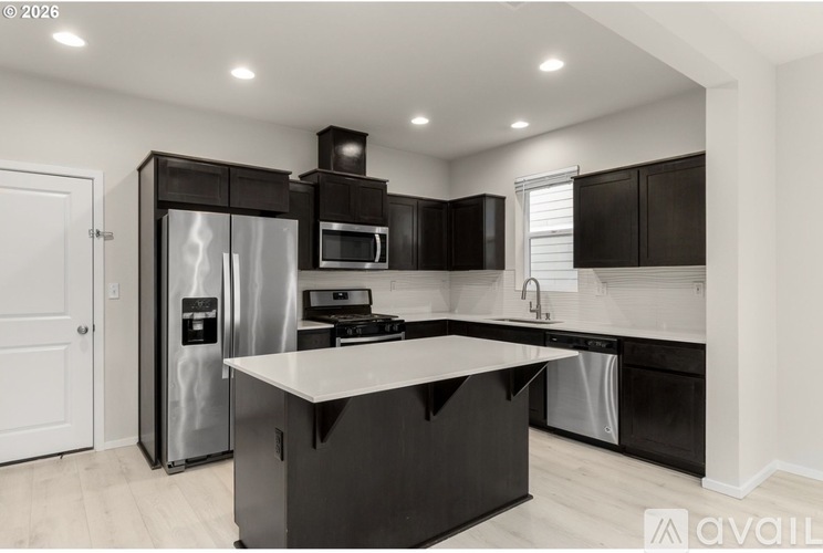 A modern kitchen with black cabinets and stainless steel appliances.
