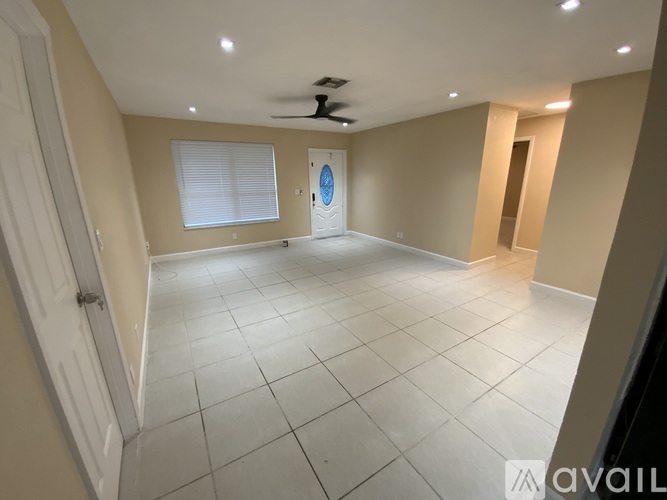 A spacious room with a ceiling fan and a door leading to another room.