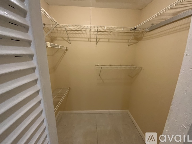 A small, empty walk-in closet with white shelving and a white staircase on the left.