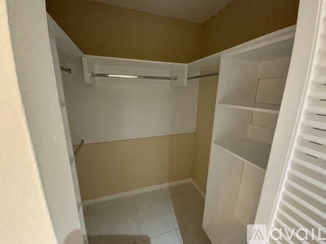 A small, empty kitchen with white cabinets and a white door.