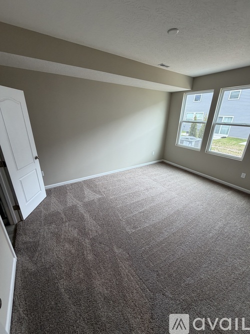 A room with a carpeted floor and a window showing a building outside.