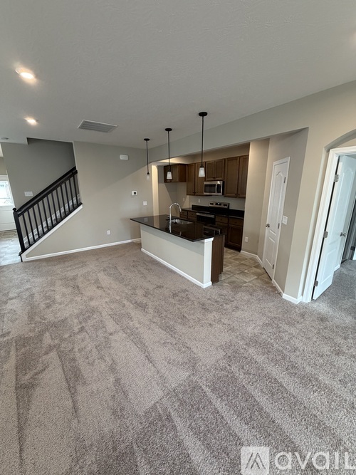 A spacious living room with a carpeted floor and a staircase leading to the upper level.