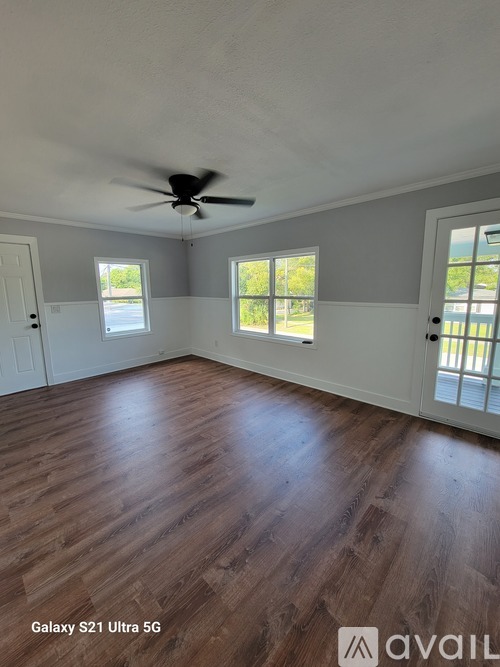 A room with a ceiling fan and wood flooring.