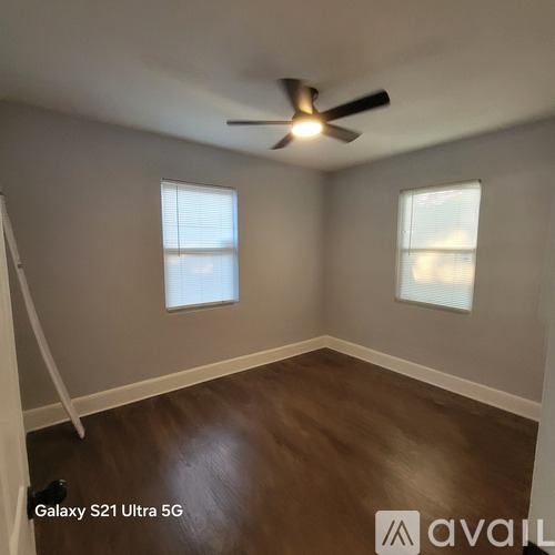 A room with a ceiling fan and two windows.