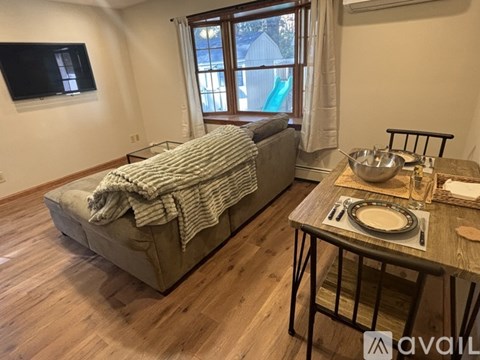 A living room with a grey couch and a wooden dining table.