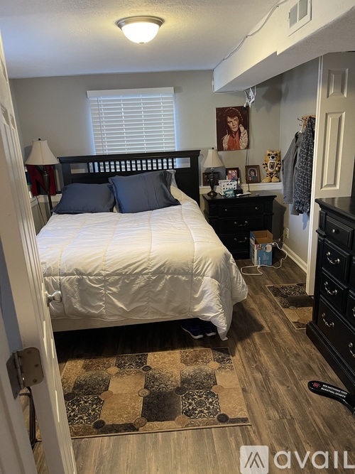 A bedroom with a white bed and a brown rug.