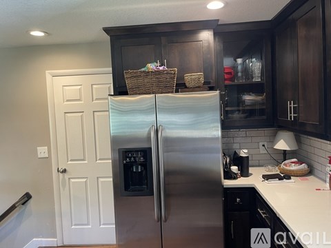 A kitchen with a stainless steel refrigerator and wooden cabinets.