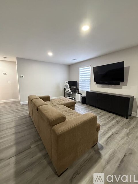 A living room with a beige couch and a flat screen TV mounted on the wall.