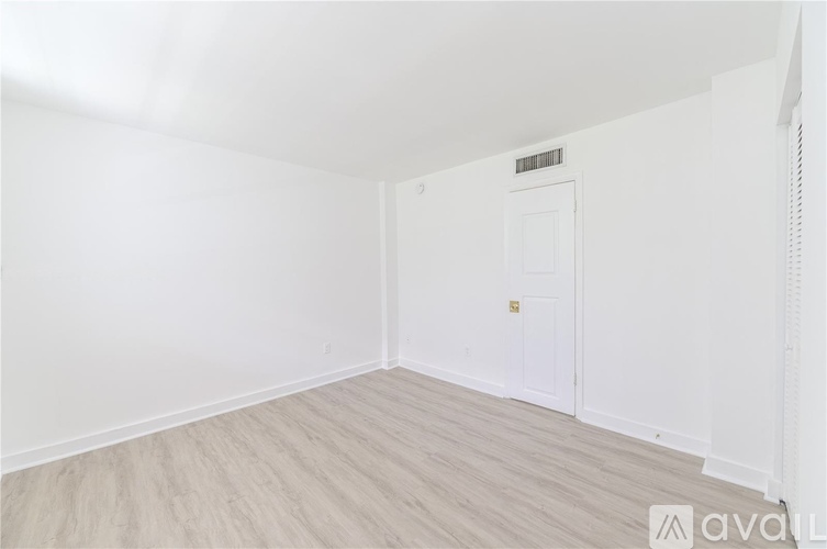 A white door is in a room with wooden flooring and white walls.