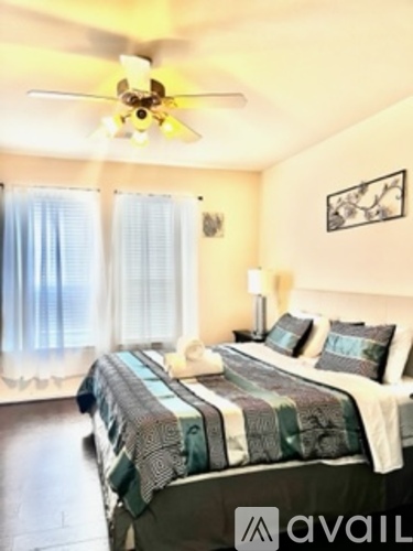 A bedroom with a bed, a ceiling fan, and a window with curtains.