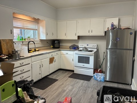 A kitchen with white cabinets and a stainless steel refrigerator.