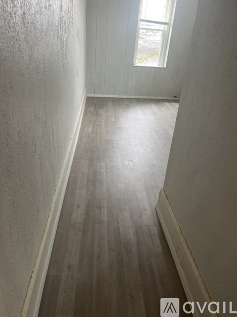 A long hallway with wood floors and white walls.
