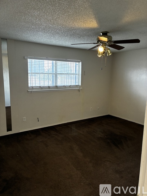 A room with a ceiling fan and a window with blinds.