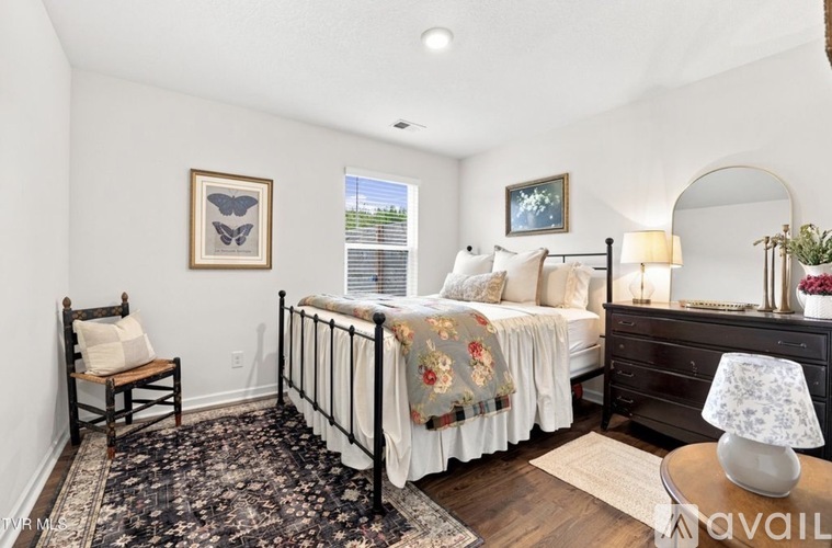 A bedroom with a bed, chair, and lamp.