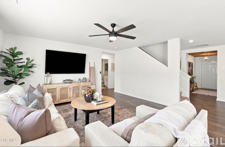 A living room with a white couch and a ceiling fan.
