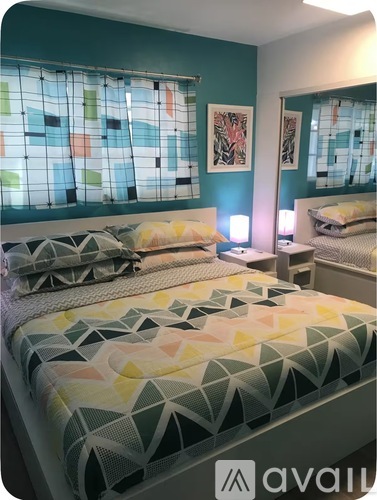 A bedroom with a bed covered in a geometric patterned bedspread.