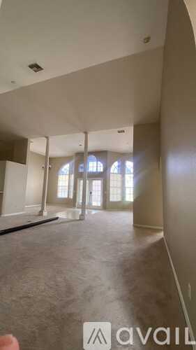 A spacious room with a long hallway leading to a door.
