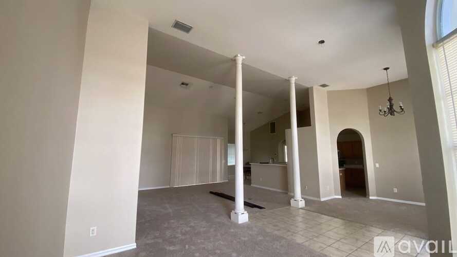A spacious living room with a high ceiling and a chandelier.