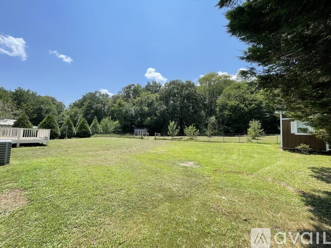 A grassy field with trees and a small building in the distance.