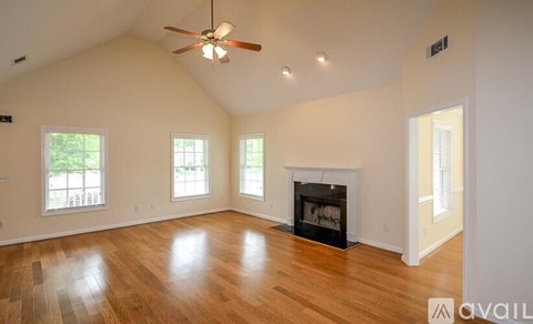 A spacious room with a fireplace and a ceiling fan.