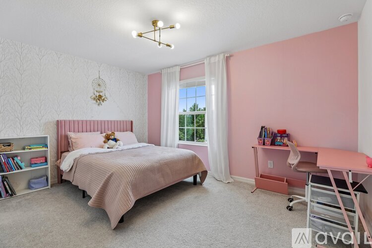 A bedroom with a pink wall and a bed with a pink blanket.