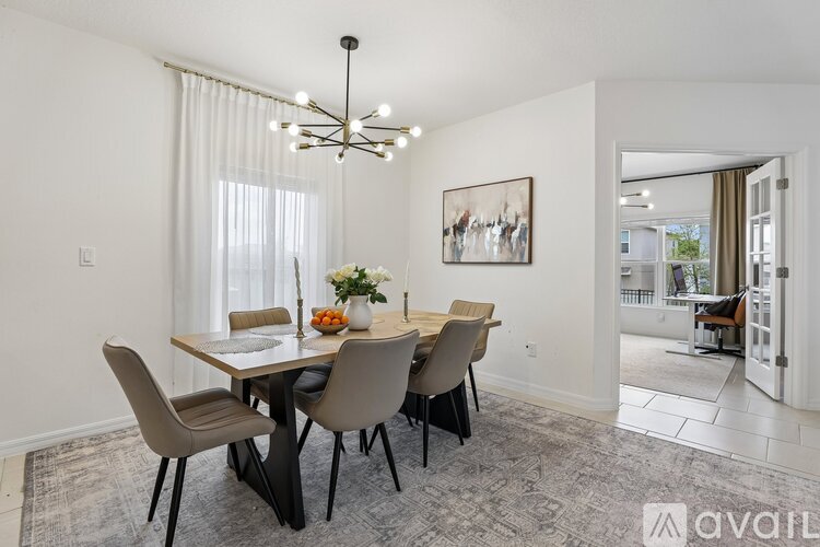 A dining room with a table set for four and a chandelier hanging from the ceiling.