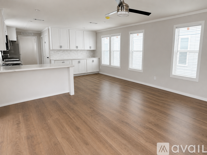 A spacious kitchen with wooden flooring and white cabinets.