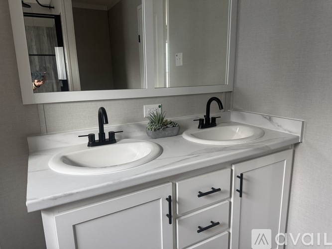 A white bathroom vanity with two sinks and a mirror.