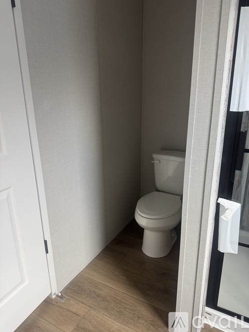 A white toilet in a small room with a door on the left.