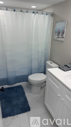 A bathroom with a toilet, sink, and shower curtain.