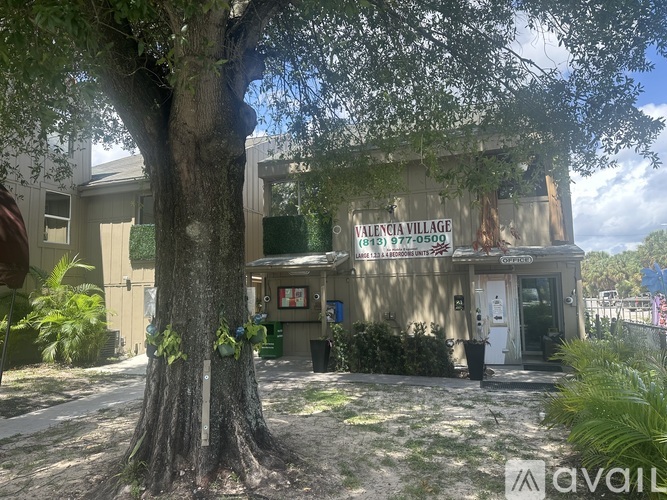 A tree in front of a building with a sign that says "Valencia Village".