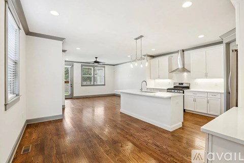 A spacious kitchen with white cabinets and a wooden floor.