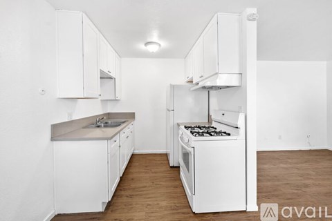 A kitchen with white cabinets and a white stove top oven.